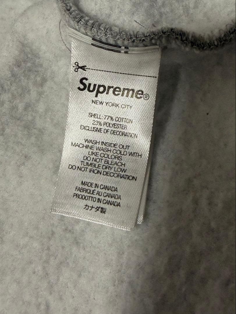 Sの刺繍が特徴のグレーのフルジップパーカー。