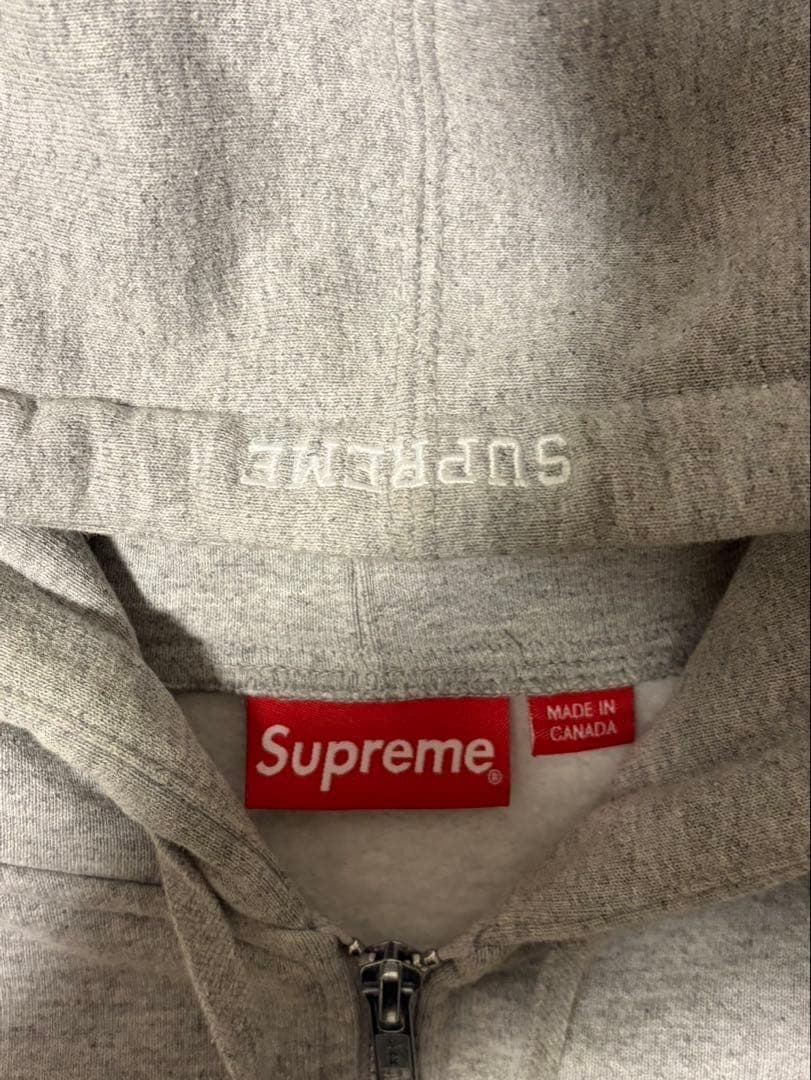 Sの刺繍が特徴のグレーのフルジップパーカー。